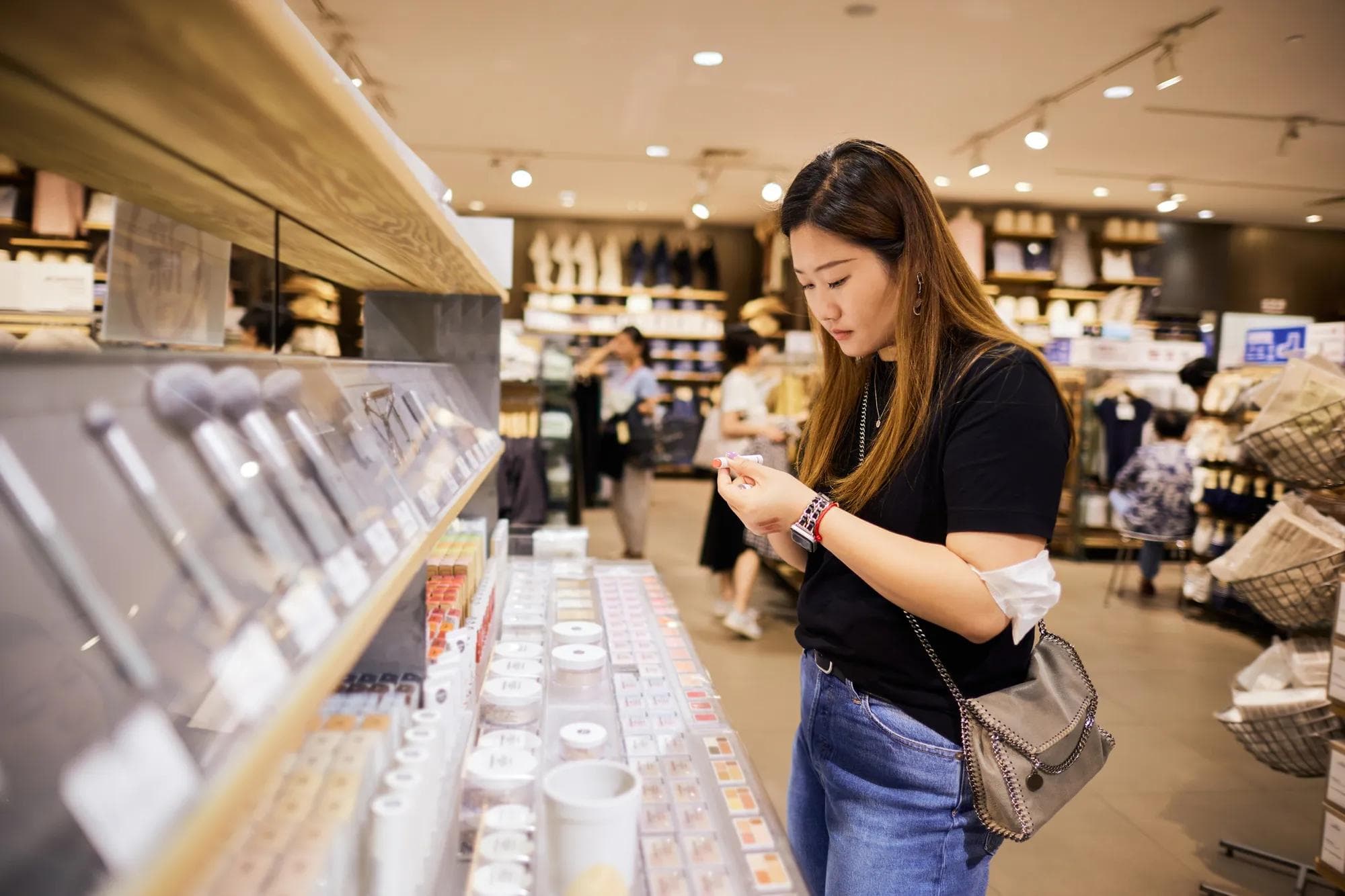 An East Asian woman chooses cosmetics in a store