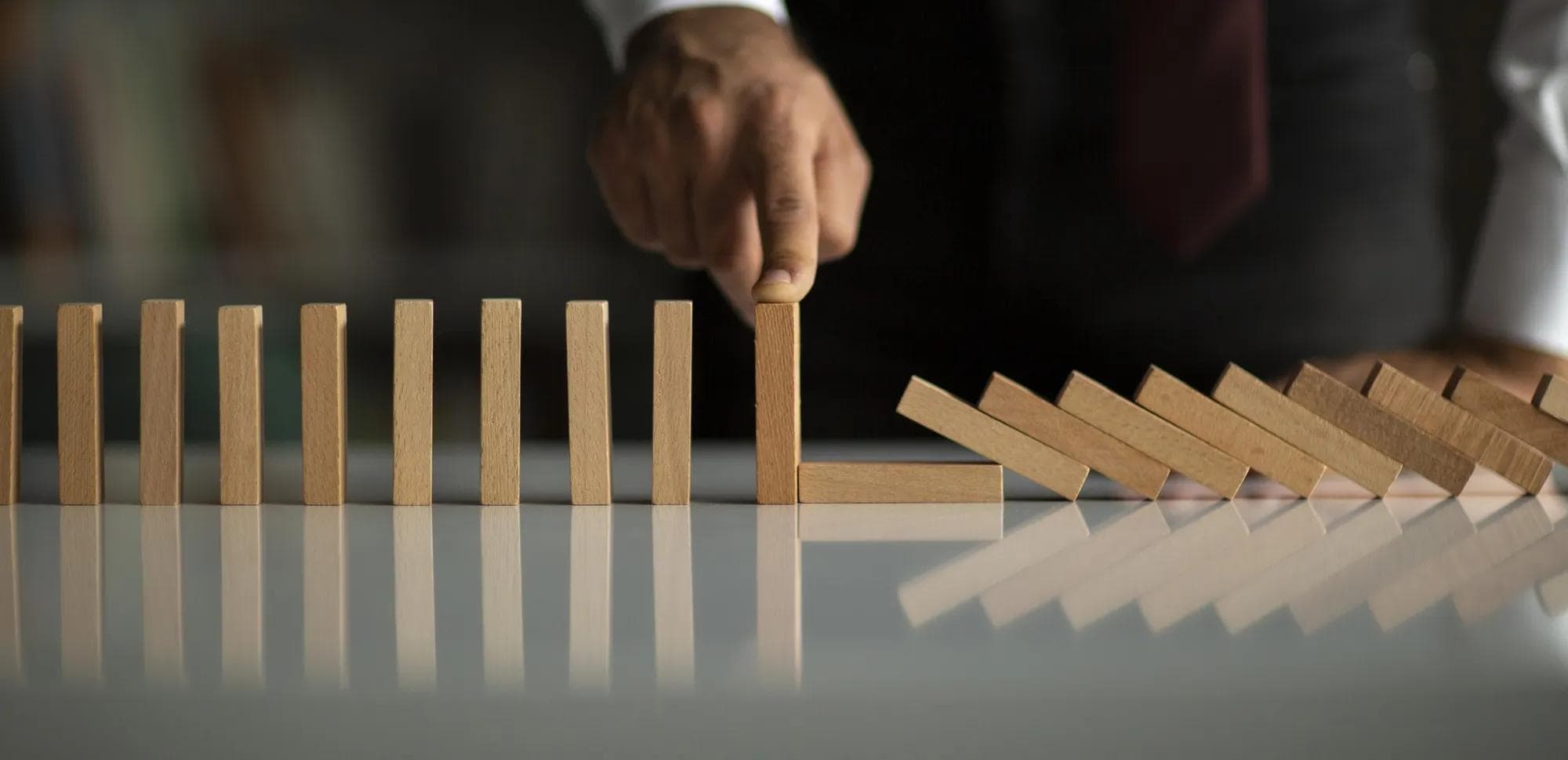 Businessman holding up a line of wooden dominos