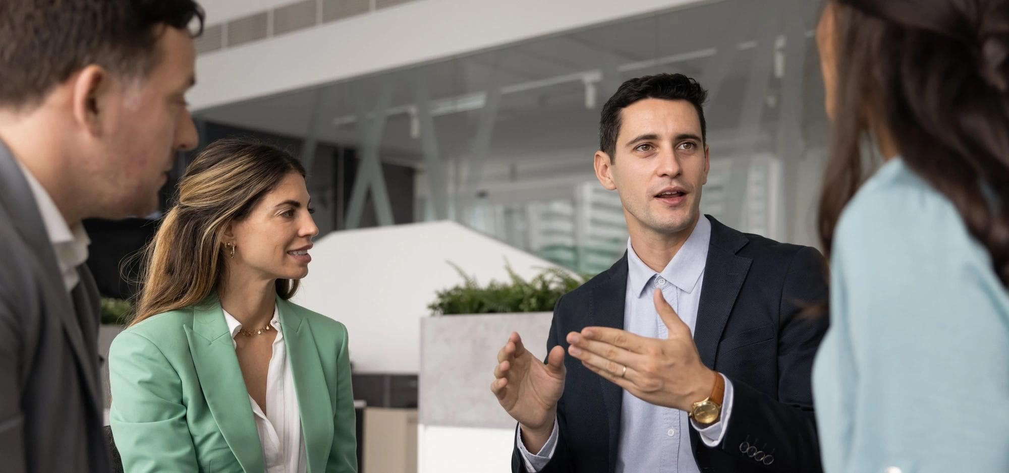Teammates in a meeting listen to a business colleague share an idea.