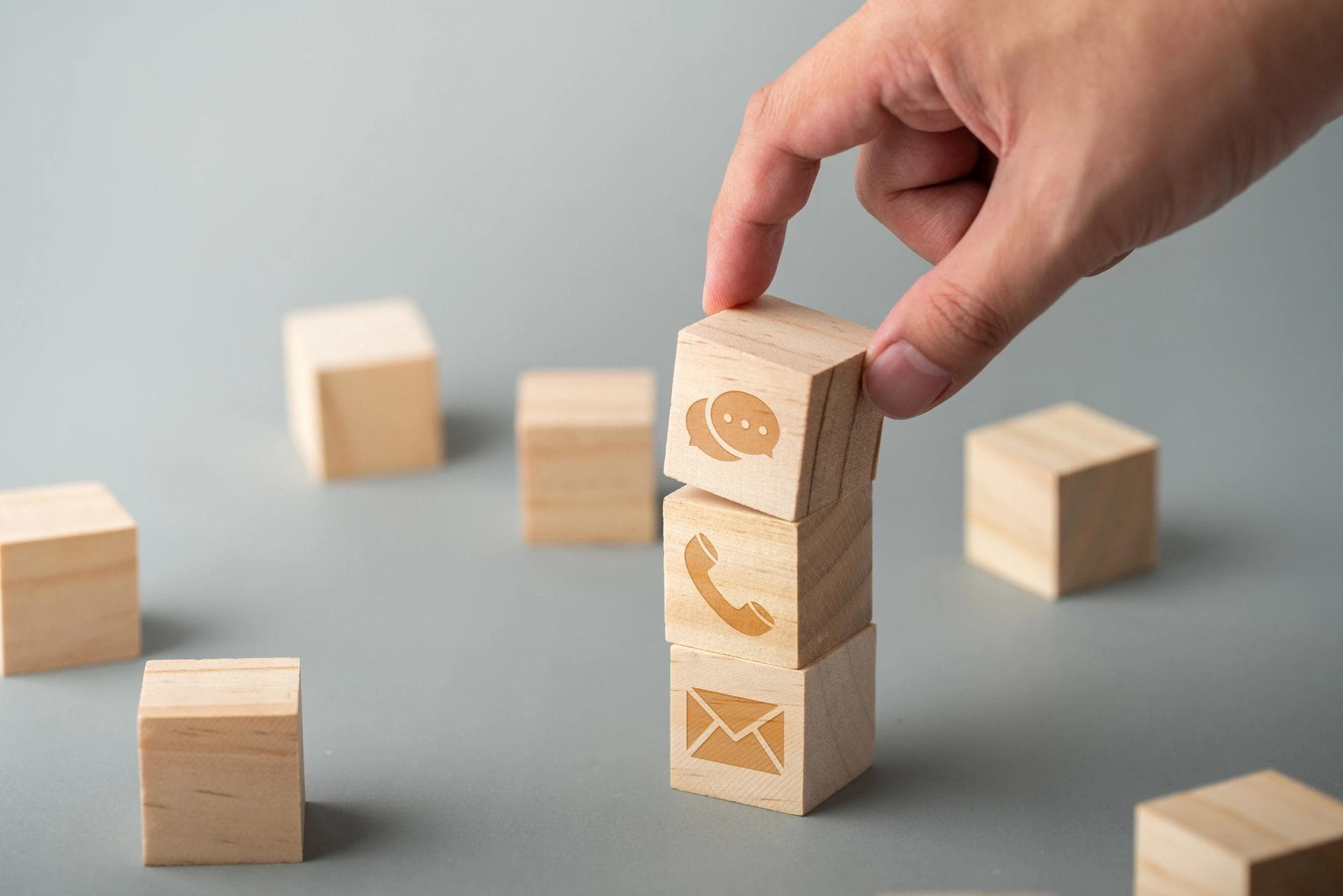 Wooden blocks with an envelope and telephone icons are stacked to represent callback requirements as a risk management practice. 