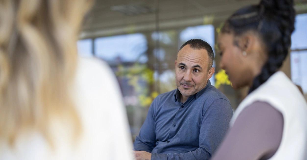 A business manager listens to feedback from his team during a meeting.