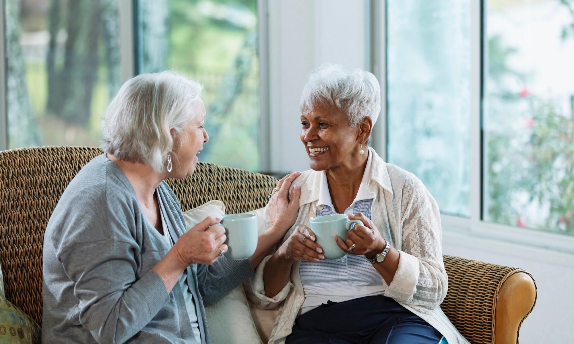 Two senior women conversing on sofa, 