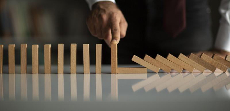 Businessman holding up a line of wooden dominos