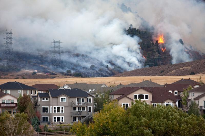 Pine trees and scrub oak burn behind homes outside of Denver, Colorado in 2010.  
