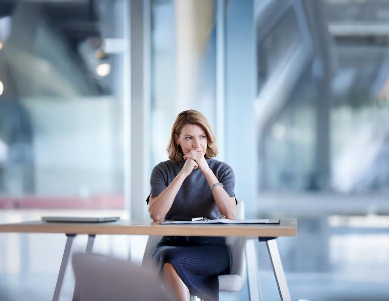 Woman thinking while looking off into the distance at her desk 