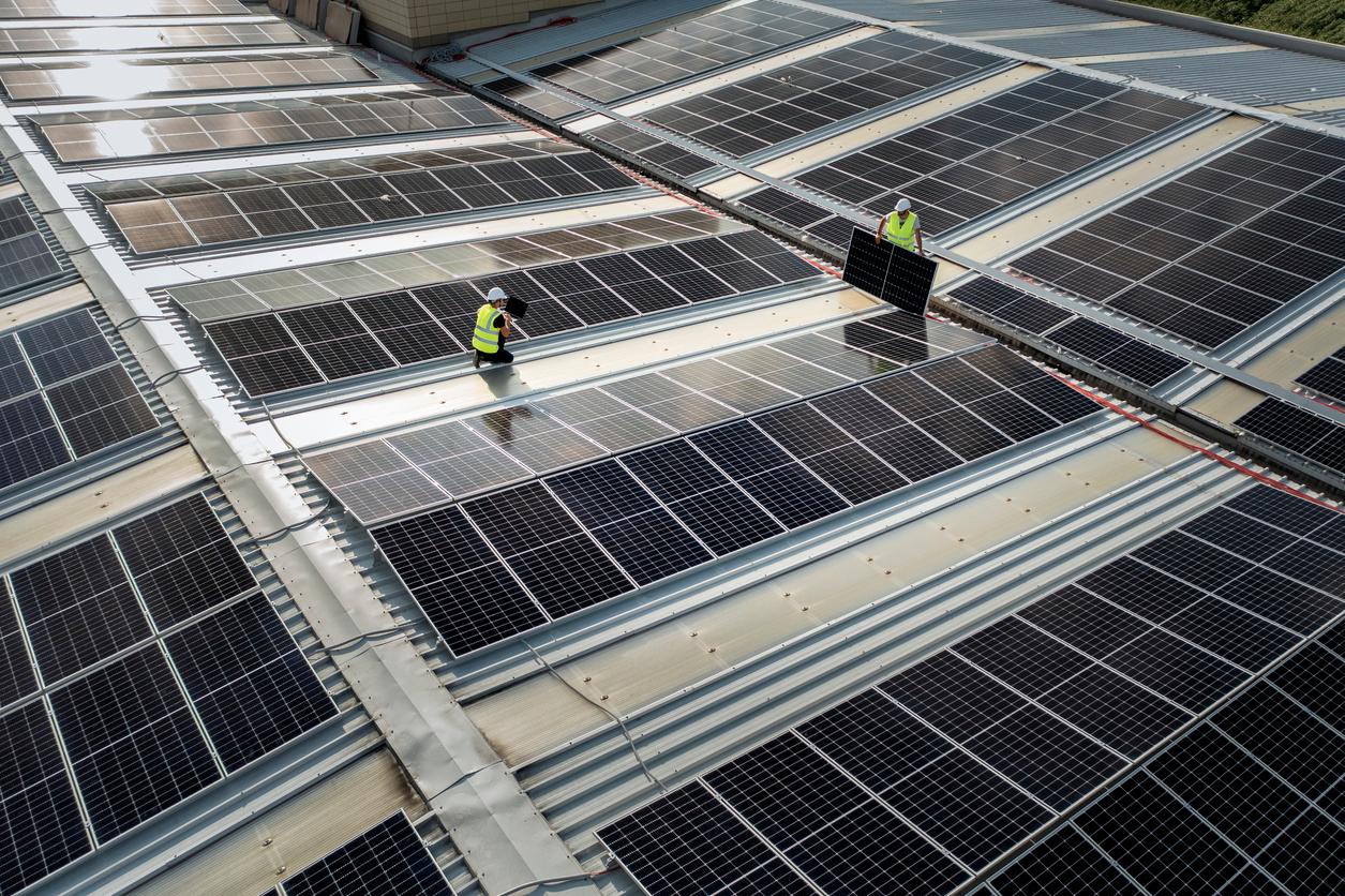 team of engineers using technology while installing solar panels on a roof of warehouse