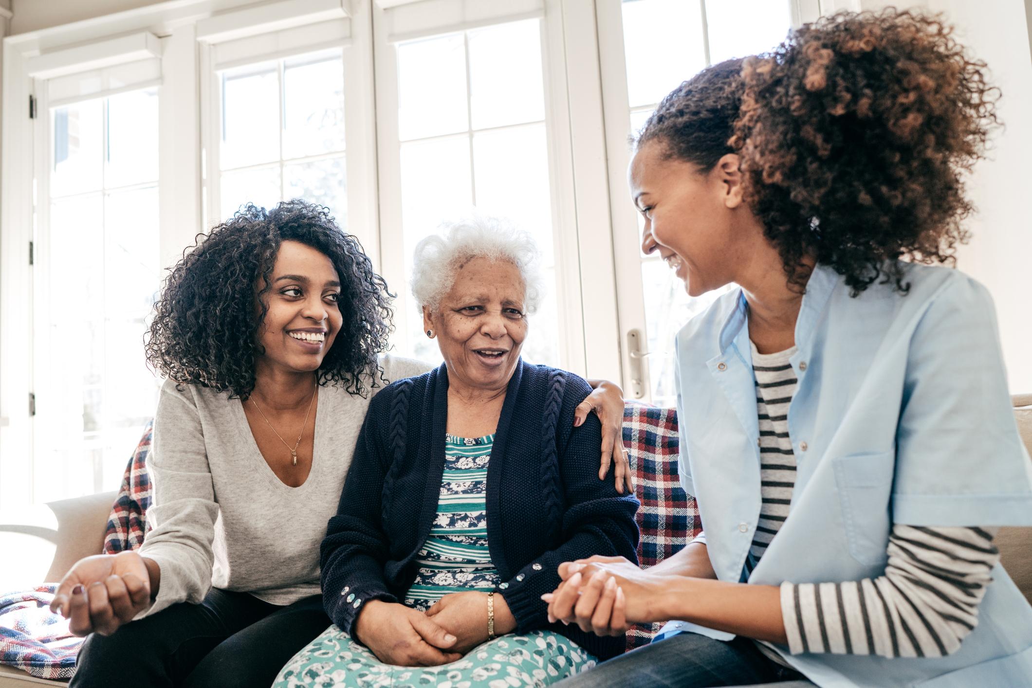 Mother and Daughter smiling with Assisted Living Caretaker