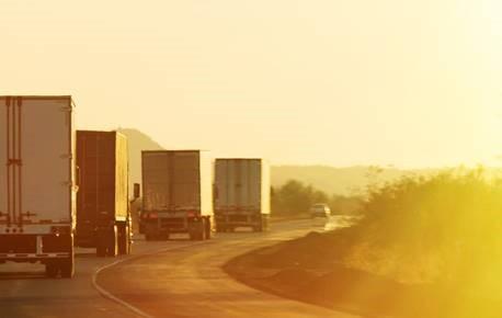 Trucks on highway at sunset