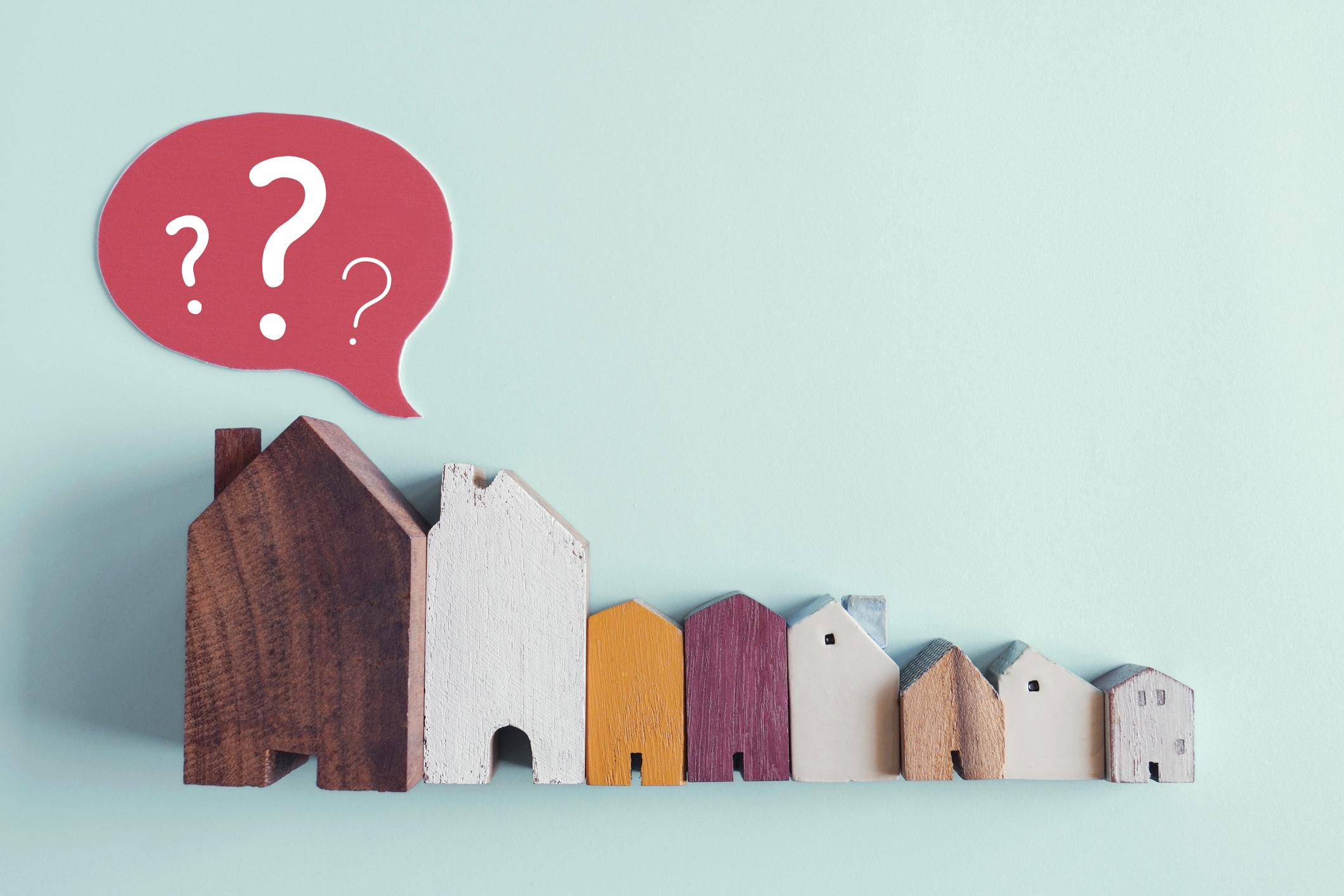 wooden house with question marks, housing crisis, confused decisions