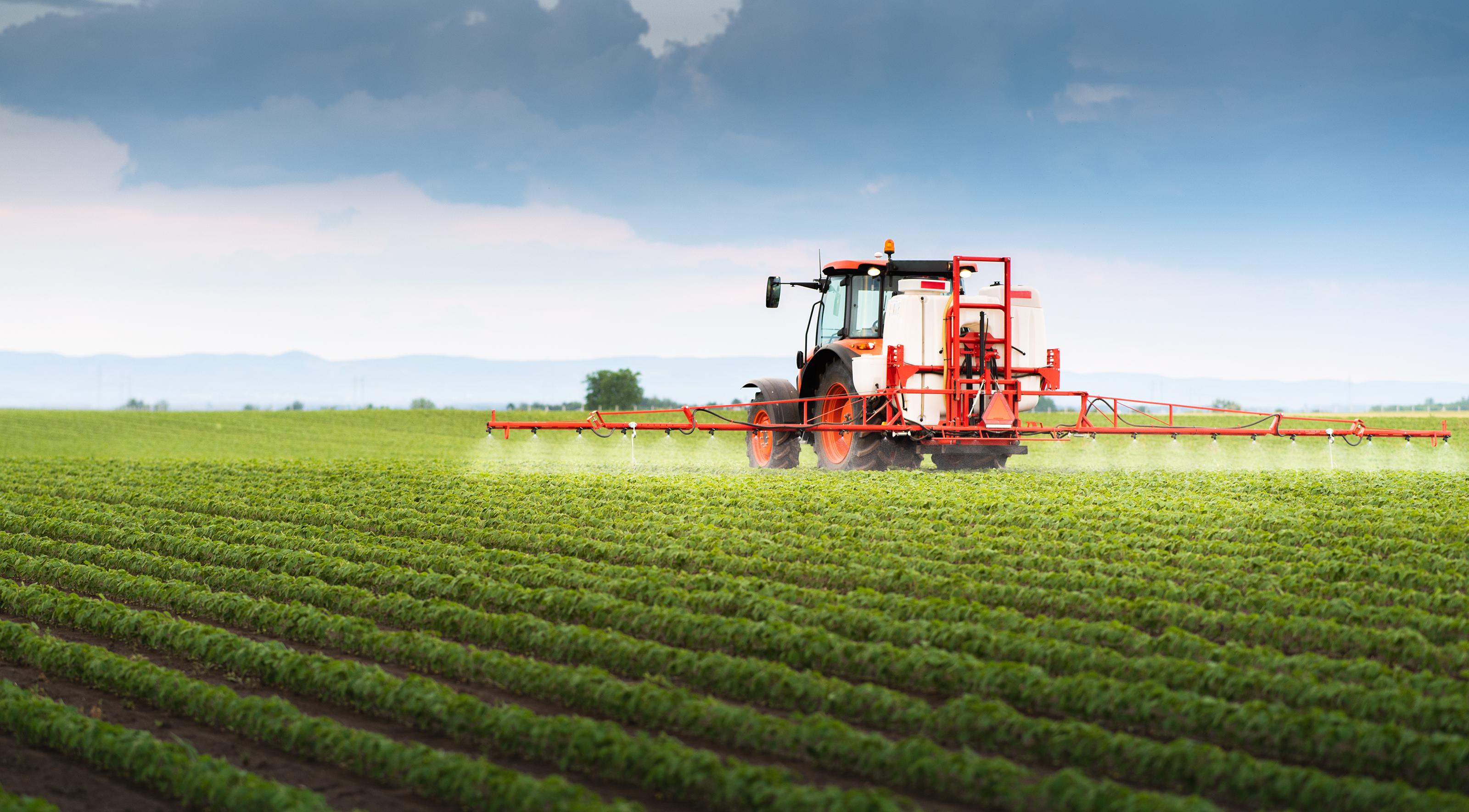 Tractor spraying soy in field.