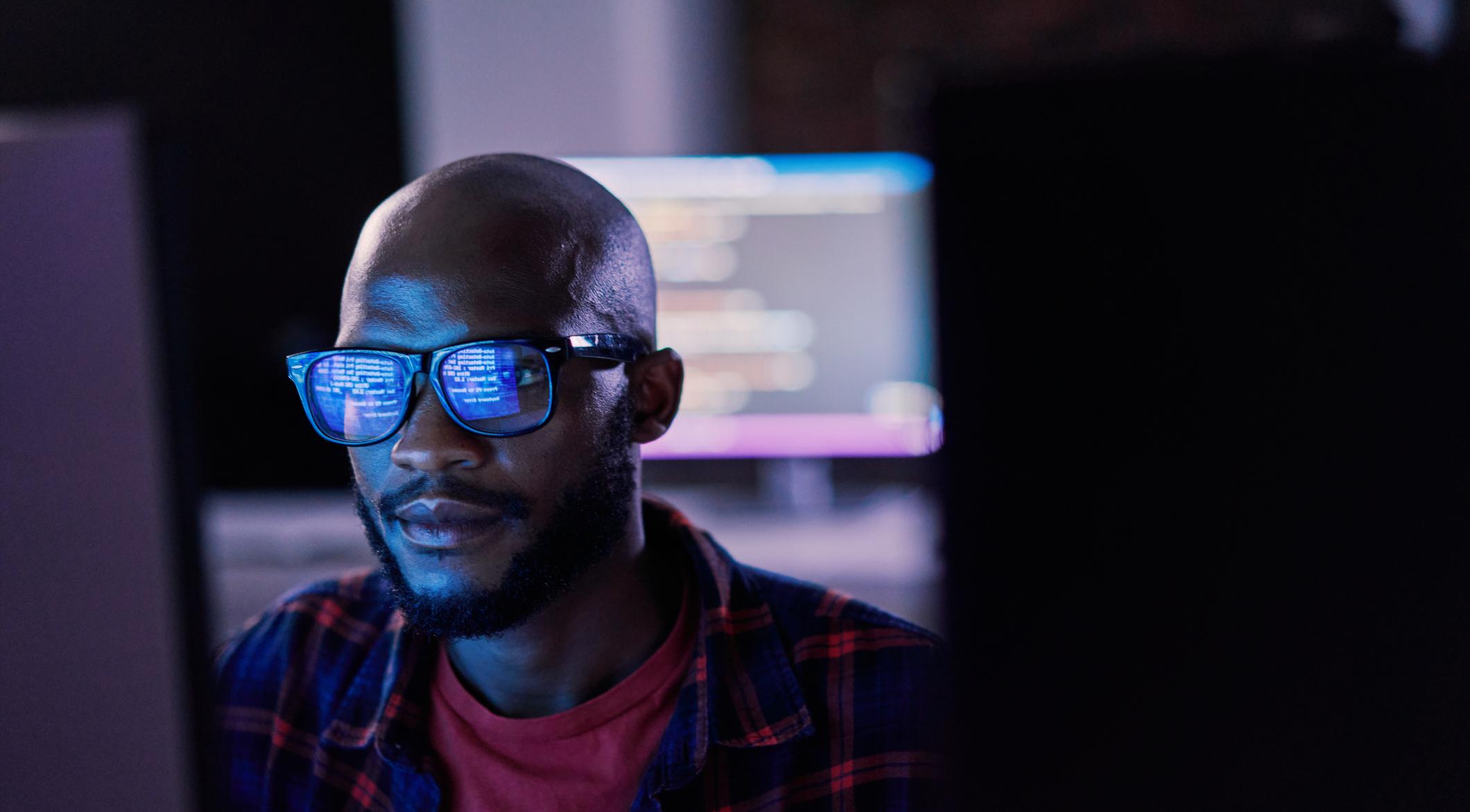 Man in front of computer screen with coding.