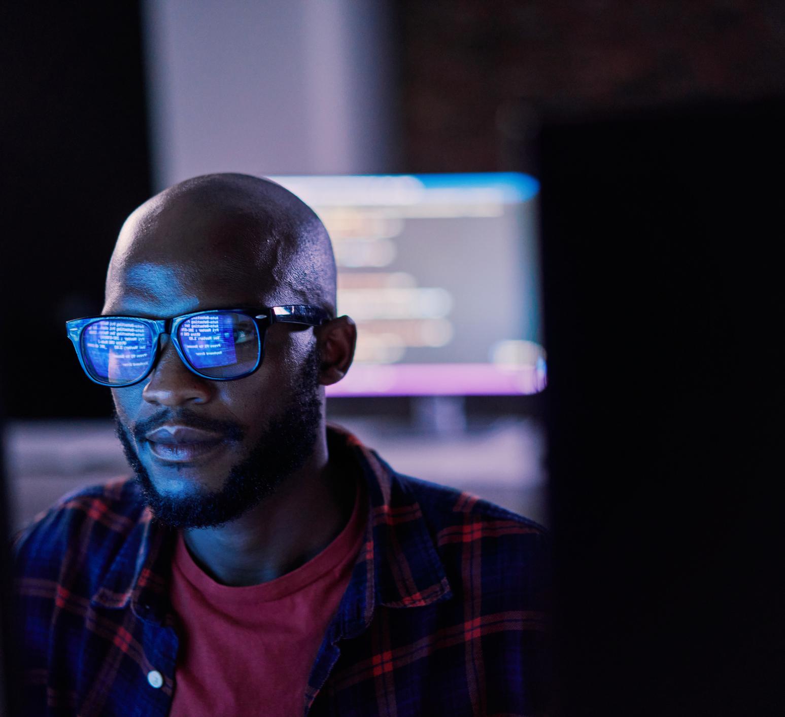 Man in front of computer screen with coding