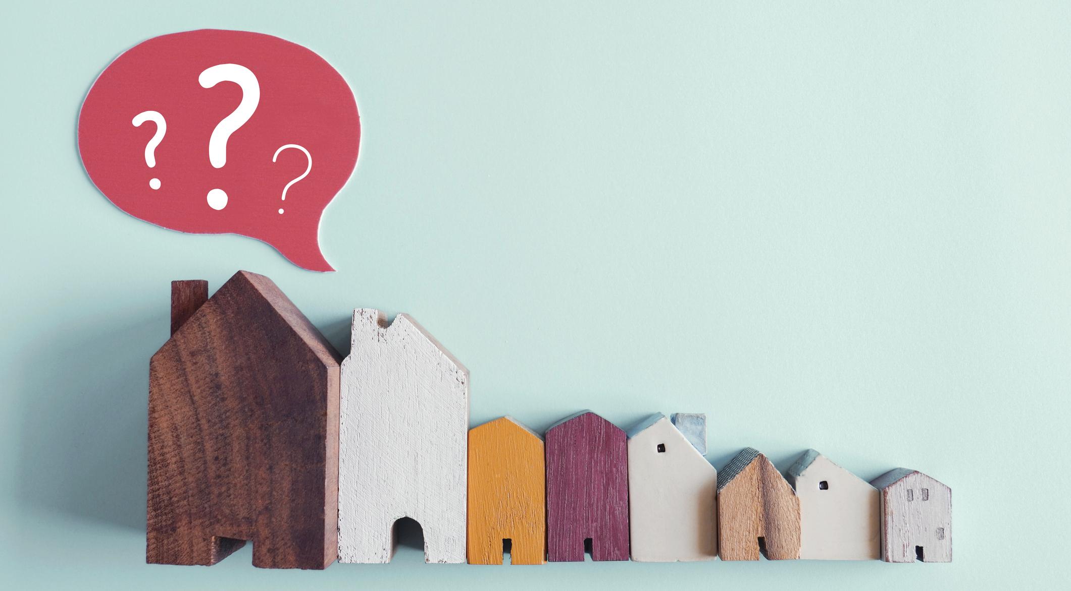 wooden house with question marks, housing crisis,  confused decisions.