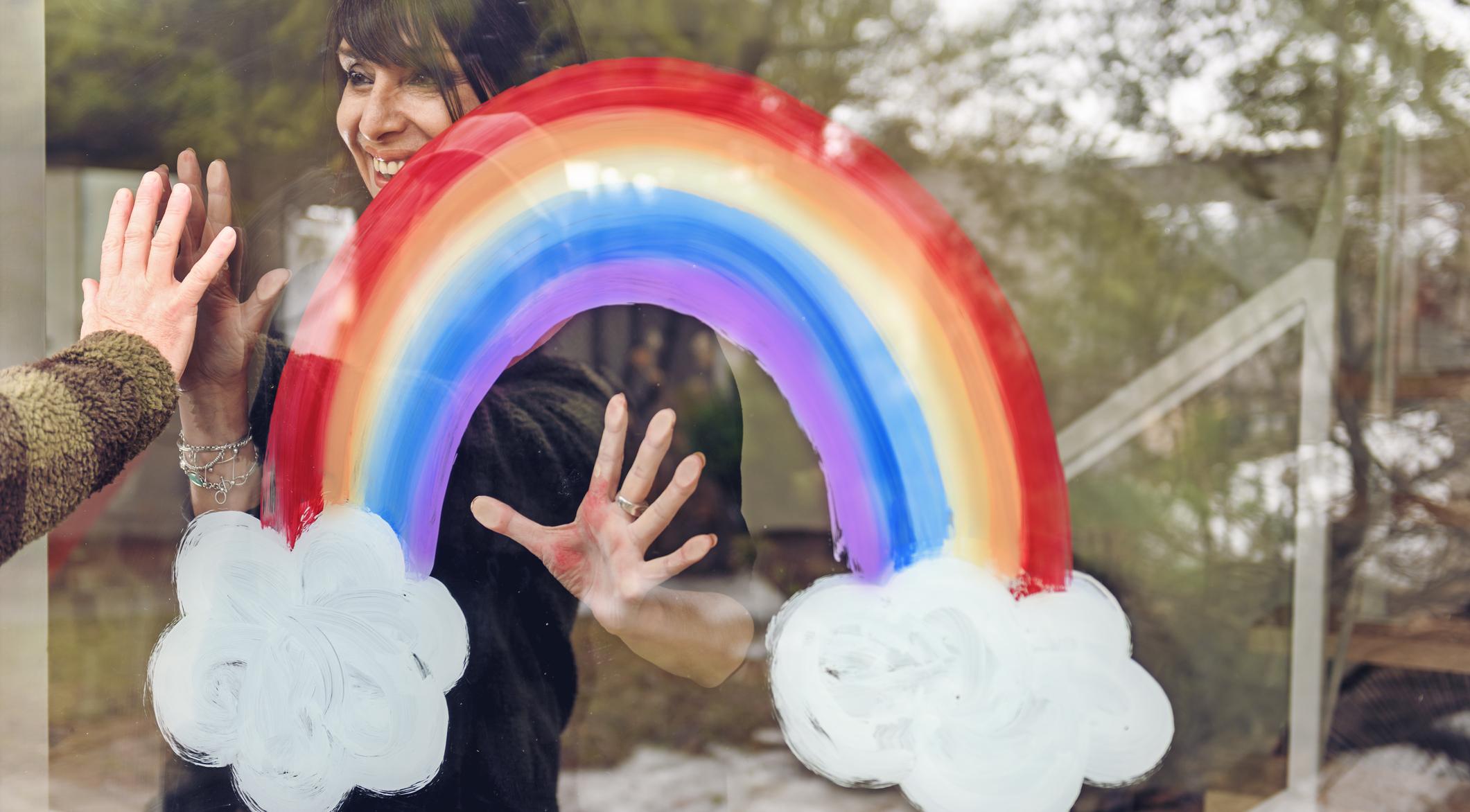 Woman looking through a window with a rainbow.