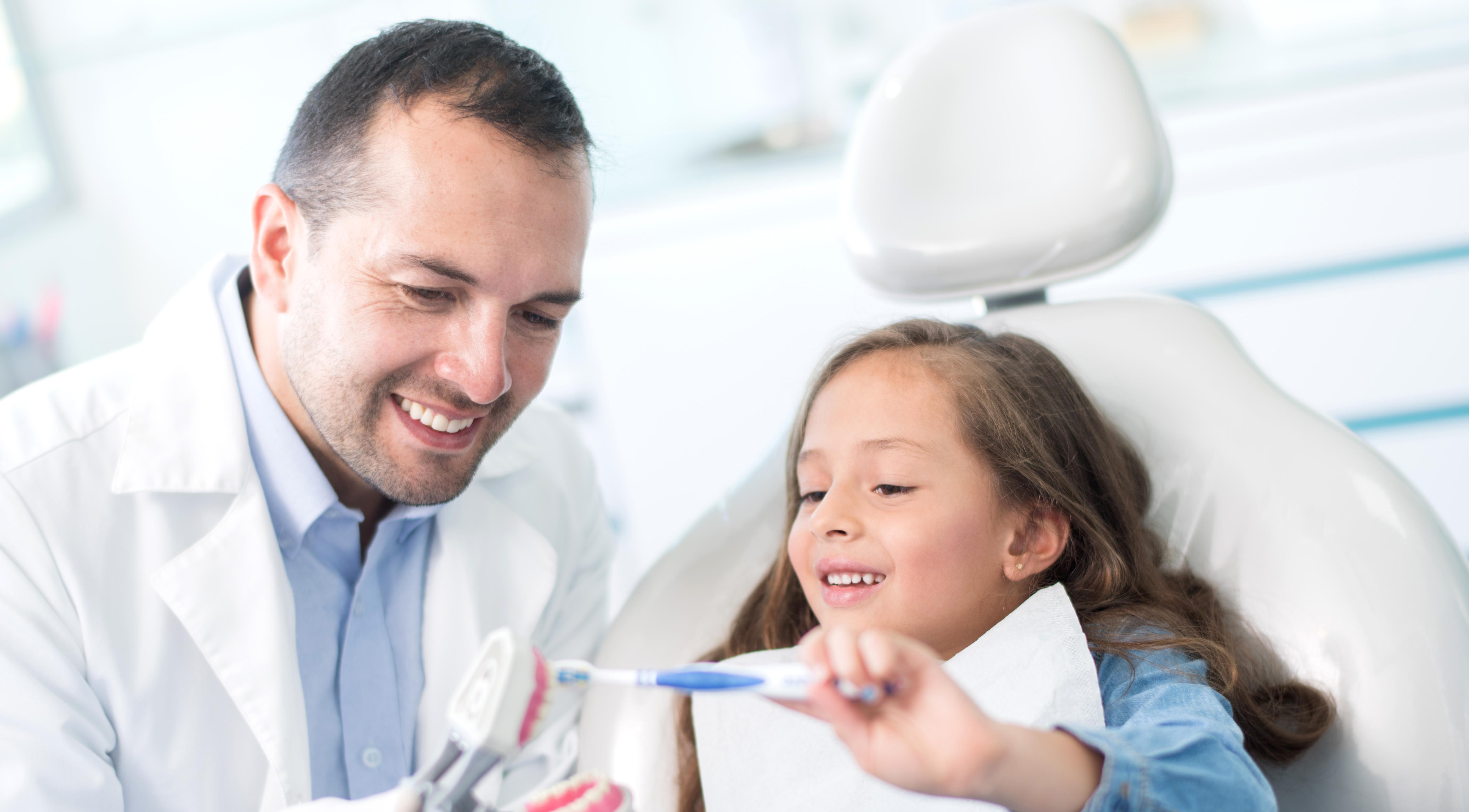 Girl at the dentist learning how to brush her teeth.