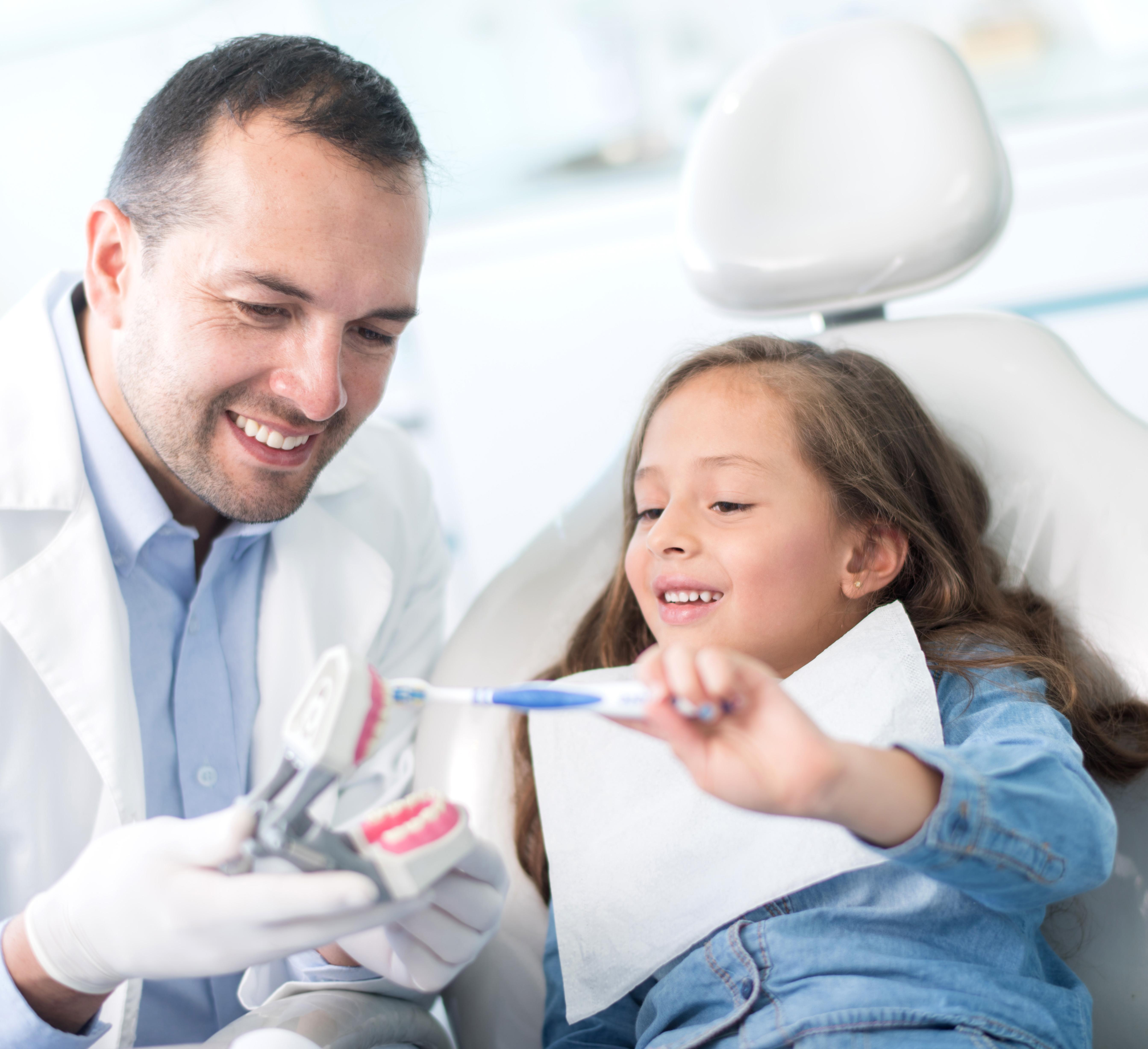 Girl at the dentist learning how to brush her teeth