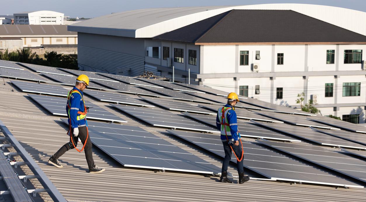 Two engineer walking on rooftop for checking solar panel.