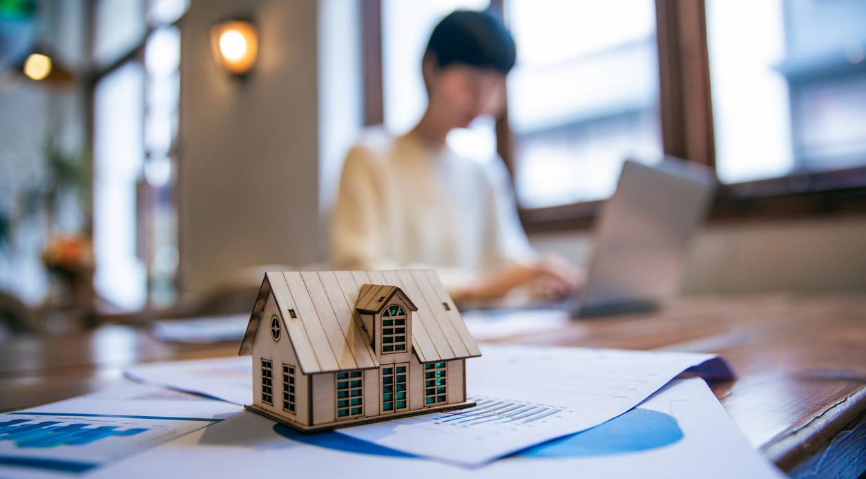 Woman working on taxes behind toy house.