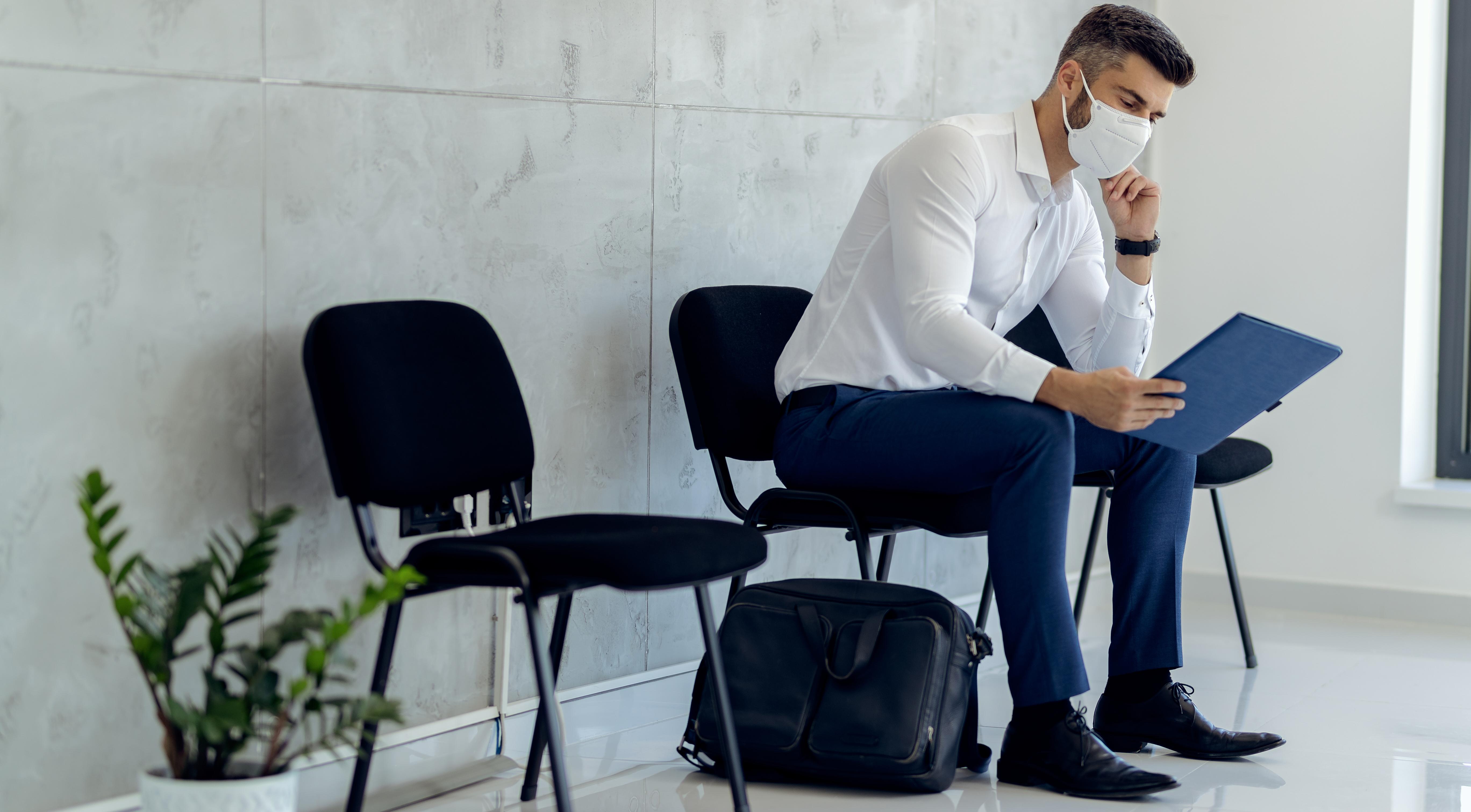 Businessman wearing protective face mask while waiting or job interview.