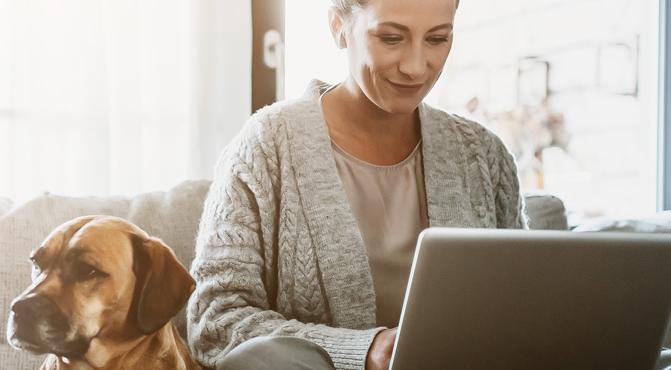 Woman working on couch with her dog.