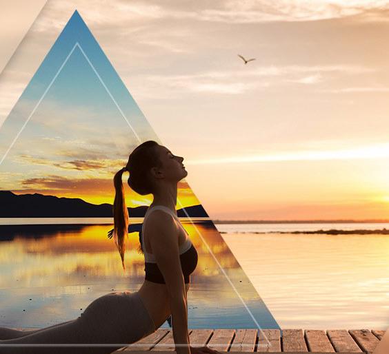 woman in yoga pose overlooking a lake at sunrise