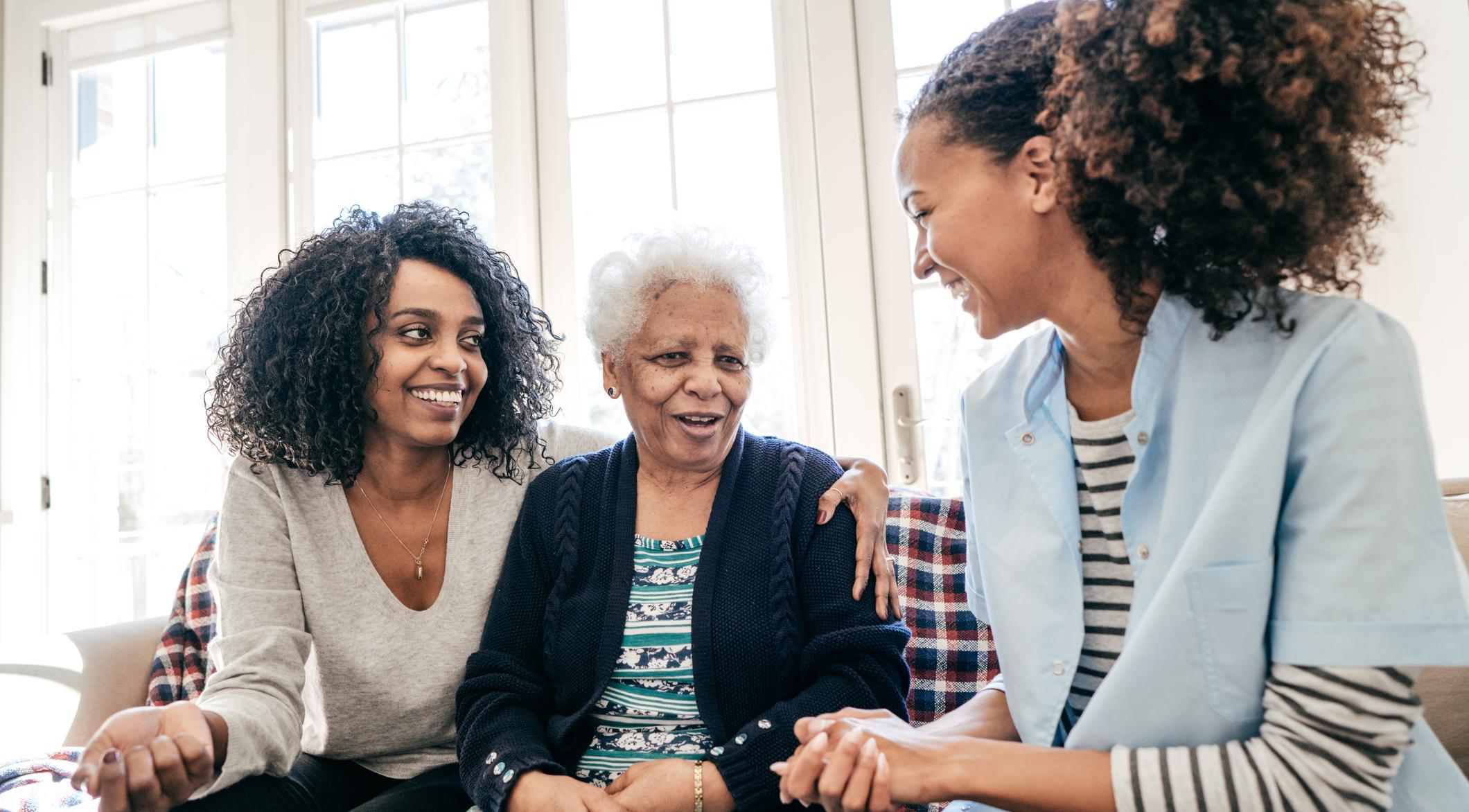 Mother and Daughter smiling with Assisted Living Caretaker.